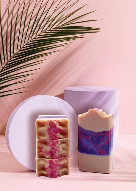 Two colorful soap bars on a pink background with a palm leaf