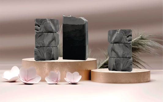 Green marbled soap bars on wooden stands with pink flowers and leaves.