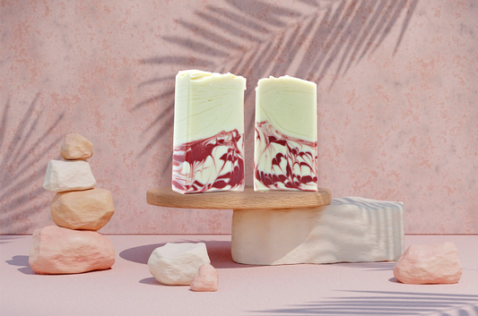 Three soap bars with a mountain design on a wooden stand against a pink background