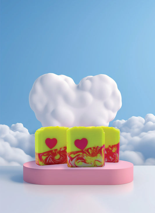 Three colorful soap bars with heart designs on a pink platform against a blue sky with clouds.