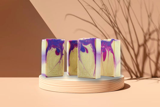 Four colorful soap bars on a round stand with a minimal background
